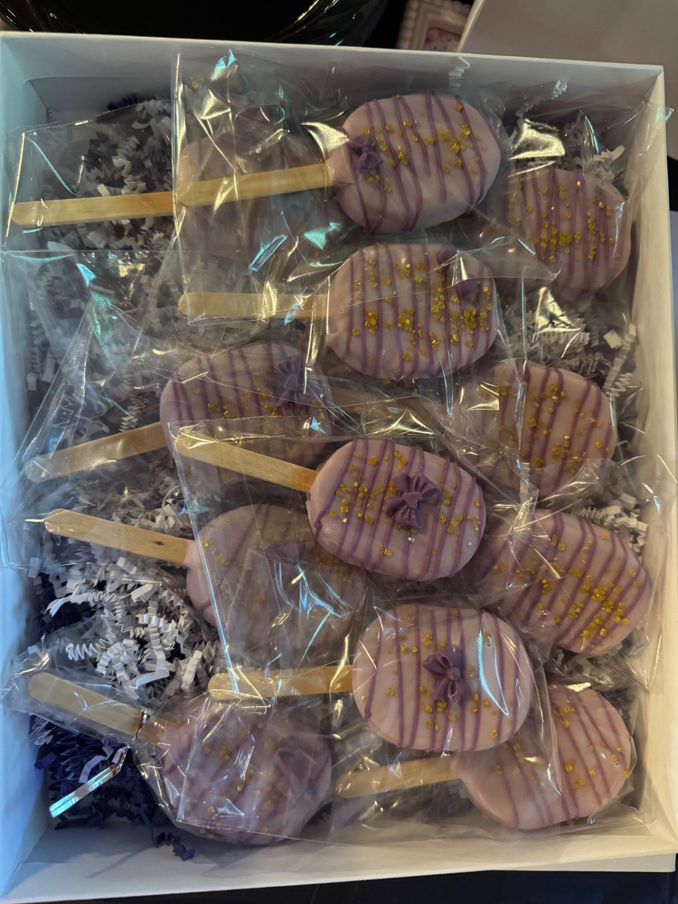 Purple and gold cakesicles in a gift box