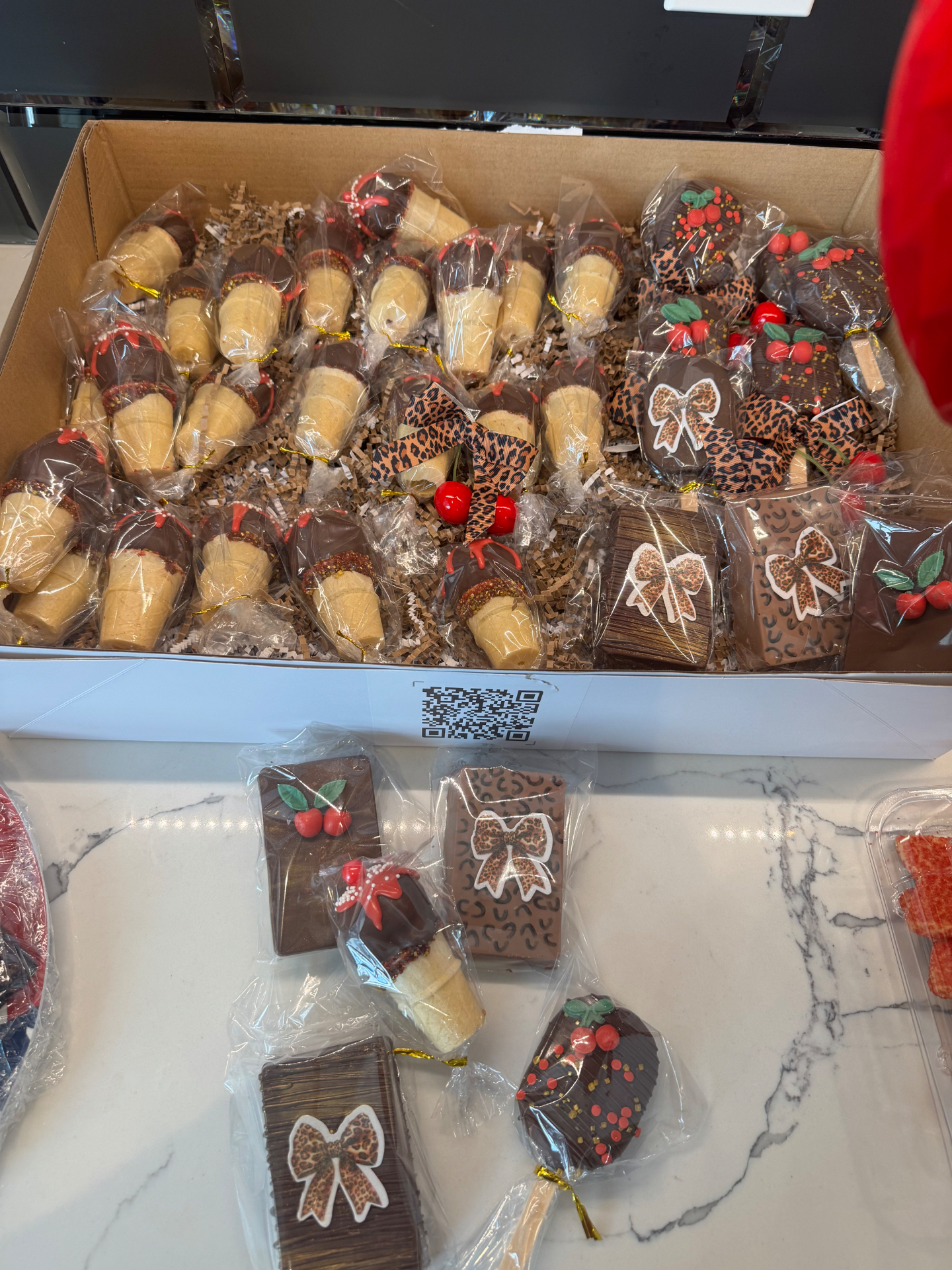 Box of cherry cheetah themed dipped sugar cones, cakesicles, and chocolate bars with leopard bows
