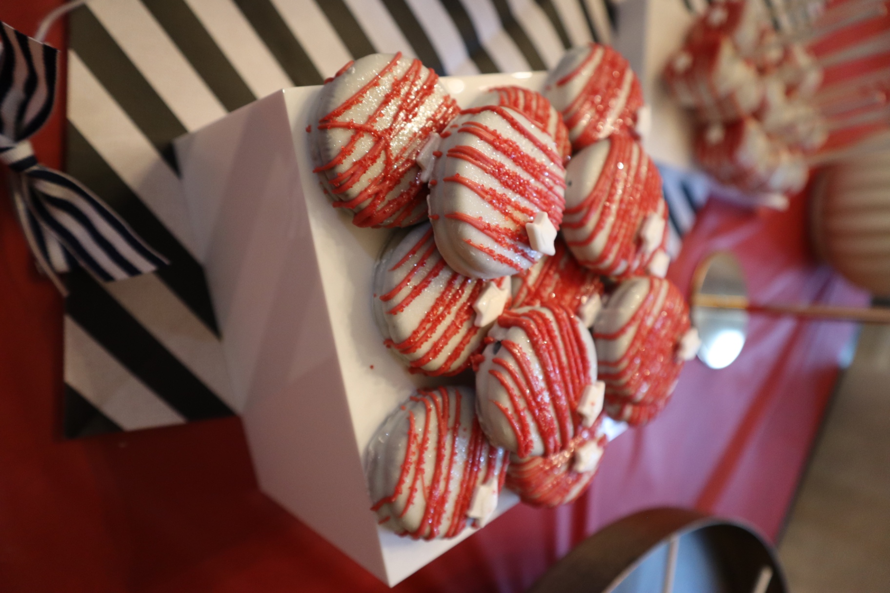 Close up of chocolate covered Oreos with red drizzle and white star accents