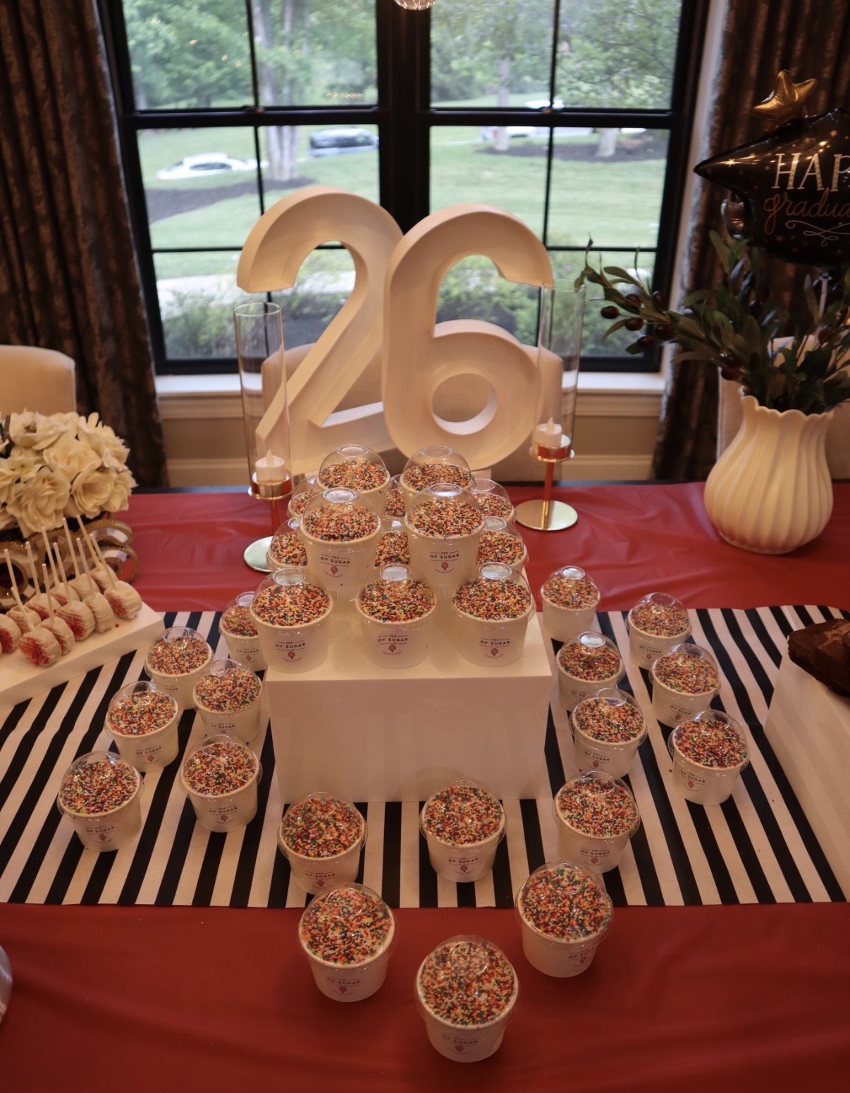 Class of 2026 display featuring many sprinkle topped dessert cups arranged around marquee numbers