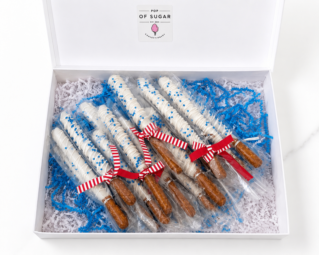 Open Pop of Sugar gift box filled with graduation party pretzel rods