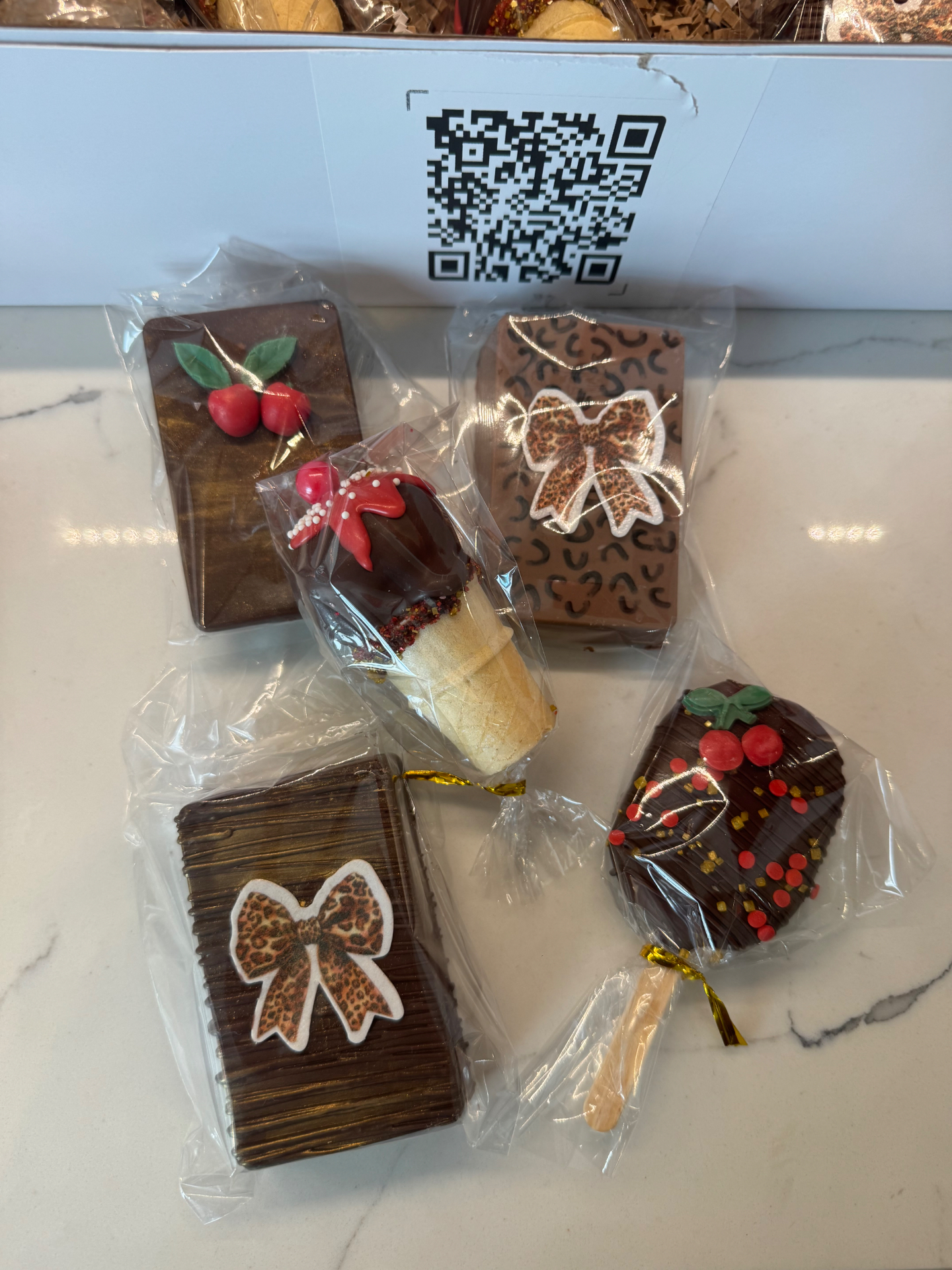 Assortment of cherry cheetah themed chocolate bars, cakesicles, and dipped sugar cones