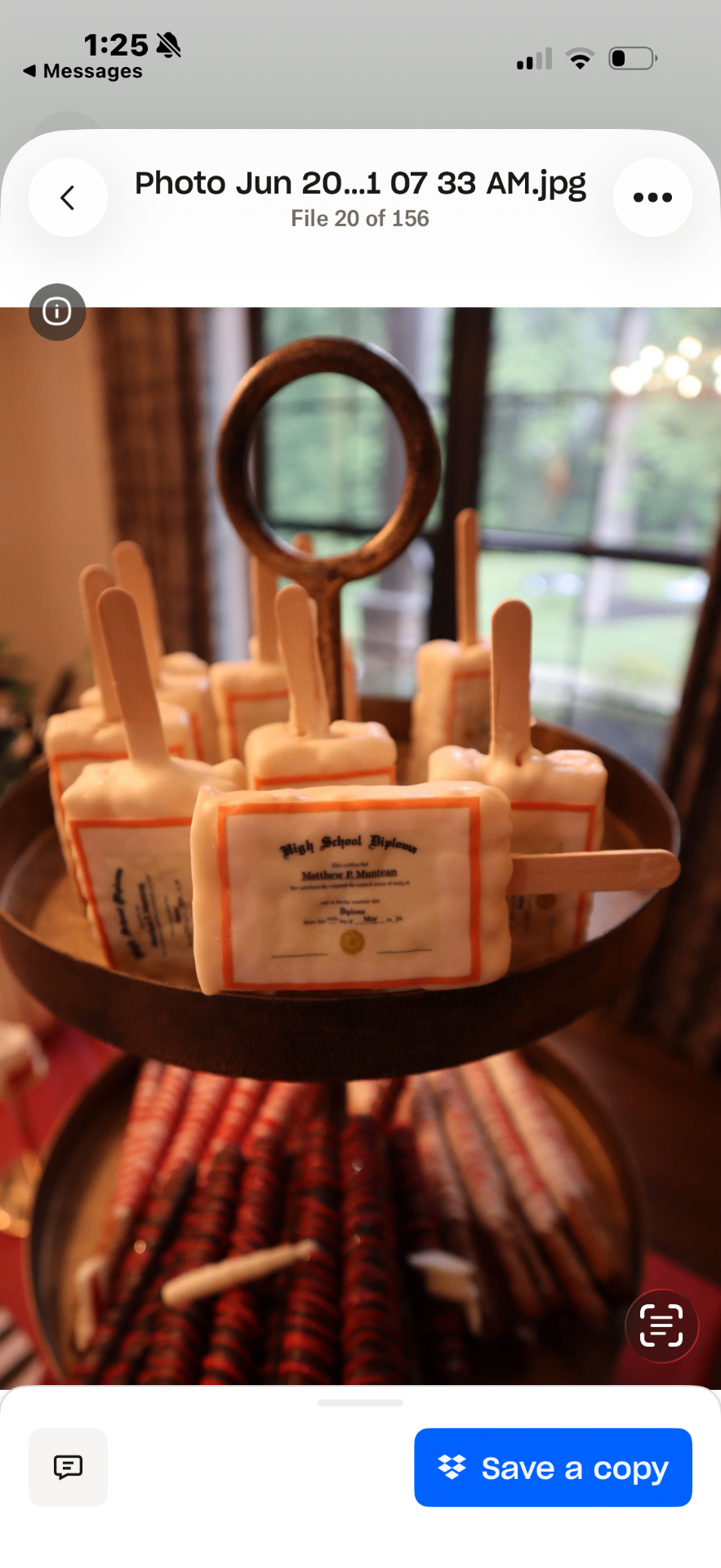 Close up of High School Diploma cakesicles on a wooden tiered stand
