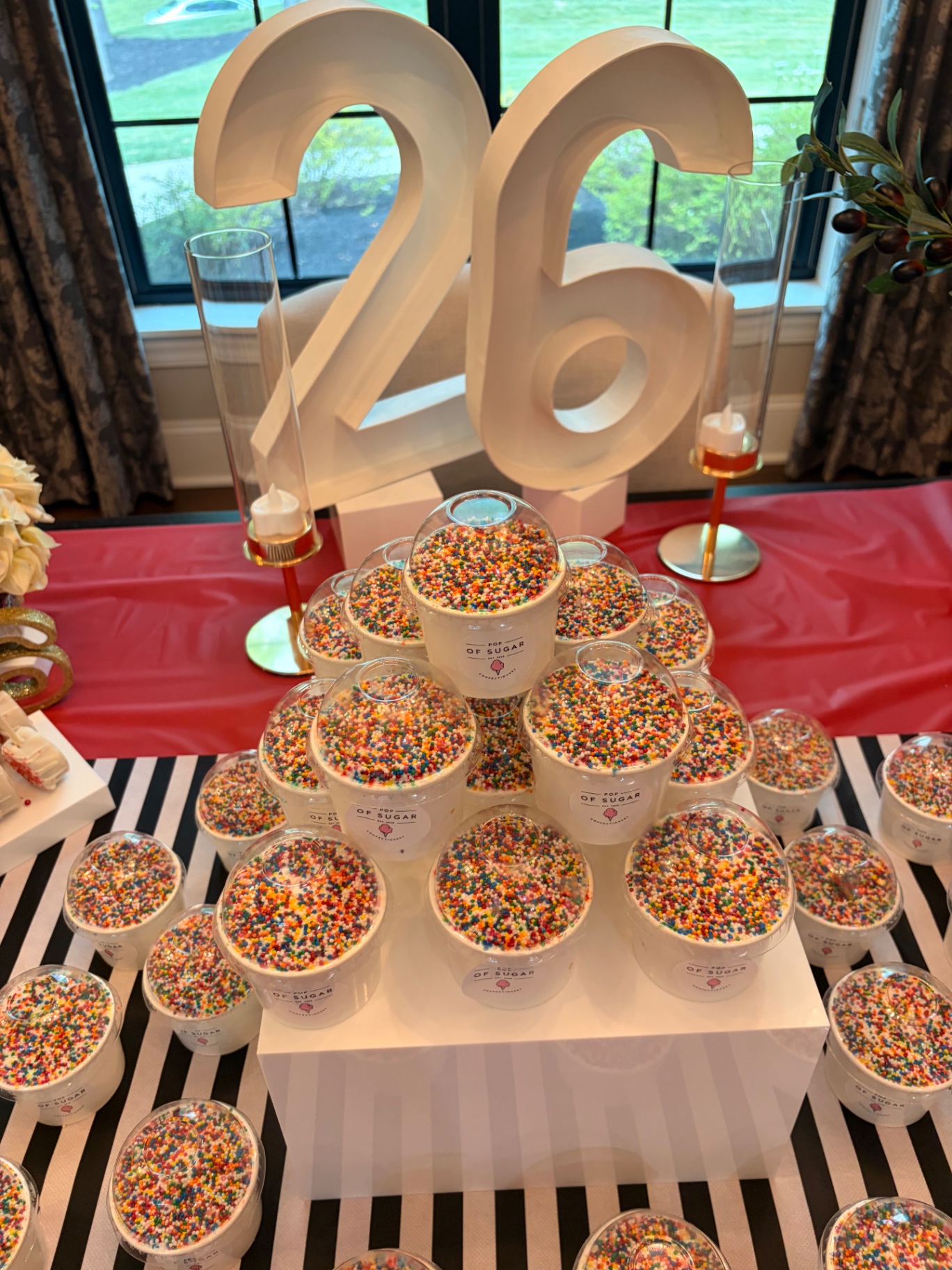 Close up of sprinkle topped dessert cups stacked beneath large 26 marquee numbers