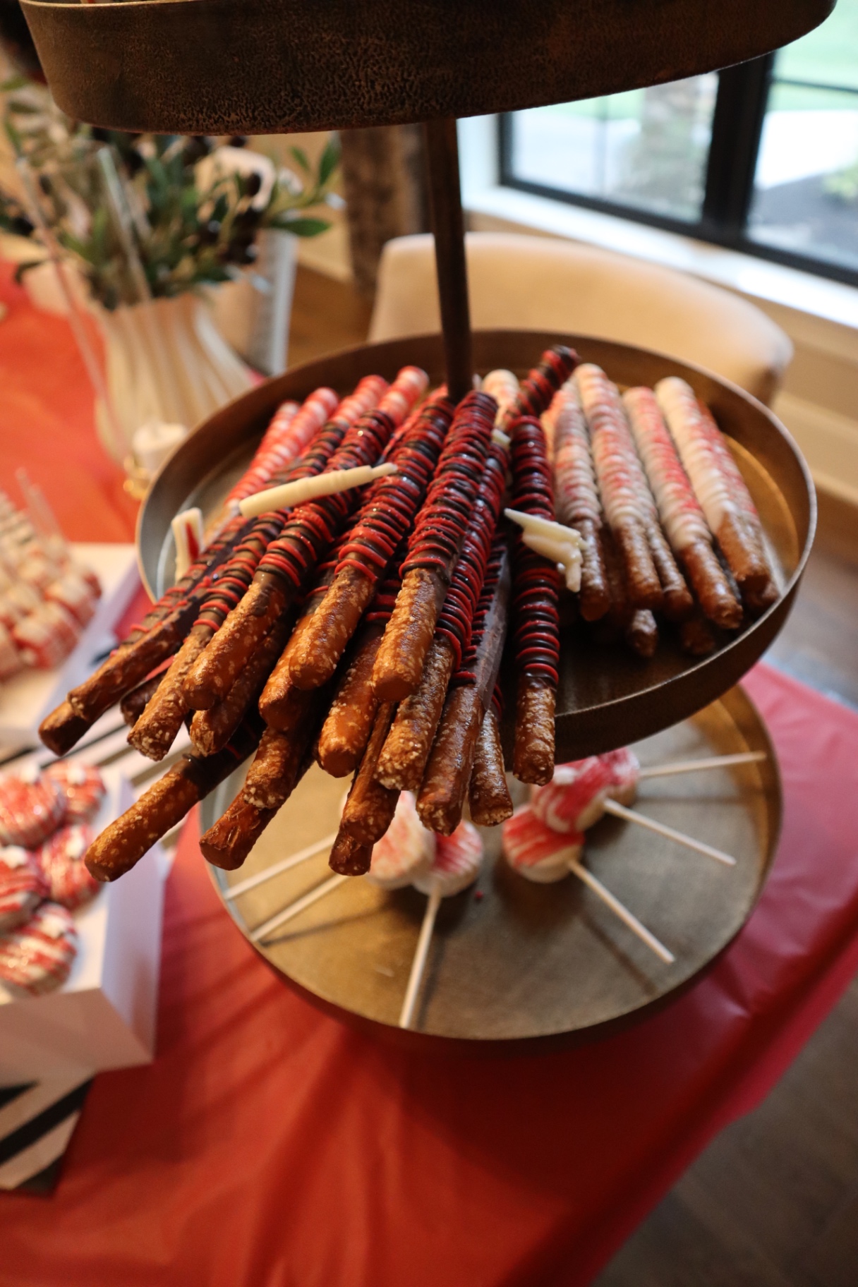 Tiered tray of red, black, and white chocolate covered pretzel rods